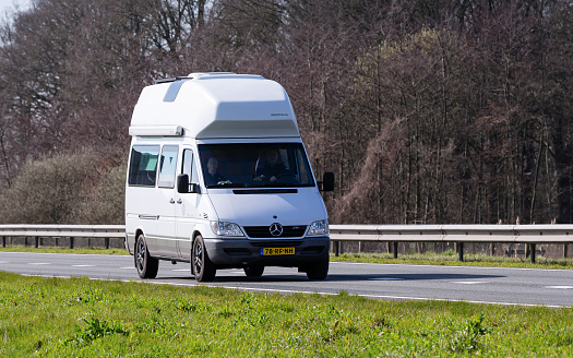 Netherlands, Overijssel, Twente, Wierden, March 19th 2023, side/front view close-up of a couple driving in a white 2005 Mercedes-Benz MkI Sprinter 316CDI van on the N36 at Wierden, the van has been converted into a motor home as a recreational 