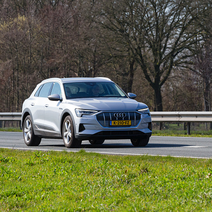 Netherlands, Overijssel, Twente, Wierden, March 19th 2023, side/front view close-up of a senior couple driving in an electric Dutch gray 2019 Audi Q8 e-tron 55 quattro station wagon on the N36 at Wierden, the Q8 e-tron is made by German  manufacturer Audi AG since 2018, the N36 is a 36 kilometer long highway from Wierden to Ommen