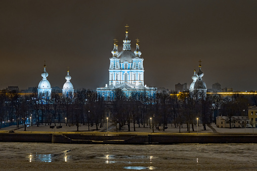 St. Petersburg, Russia - February 24, 2024. View across the frozen Okhta River to the Smolny Cathedral at night with artificial lighting.