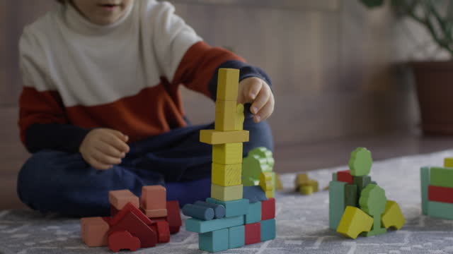 Child boy playing with toy blocks at home