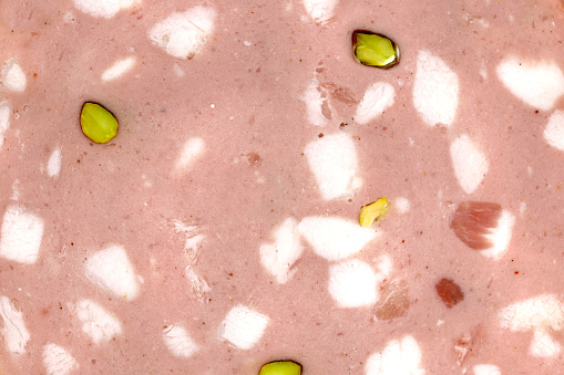 close up of sliced mortadella bologna with pistachios, top view of the texutre of a traditional italian pork sausage.