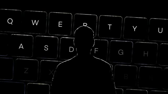 Dark silhouette of a hacker, dark keyboard with white backlight