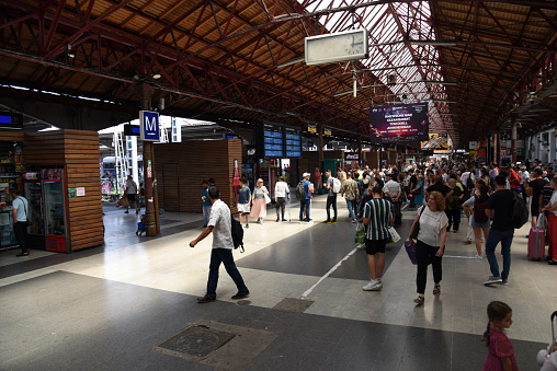 Main hall of the Bucharest North railway station. The image shows several people at the station building,  captured during summer season.
