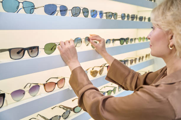 istock Lady in a brown blouse chooses sunglasses 2041045263