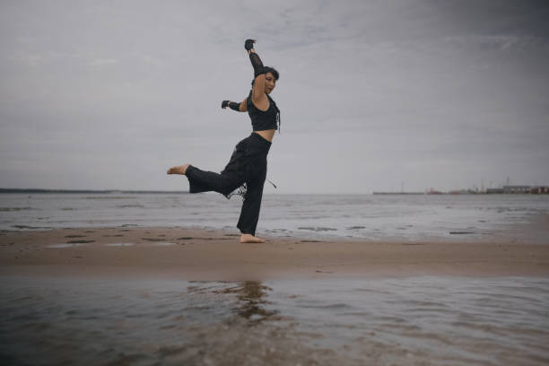 contemporary dancer in black clothes dancing in the sea. Modern dance expression, harmony with nature