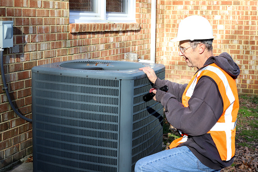 Home inspection of central air unit by a maintenance worker