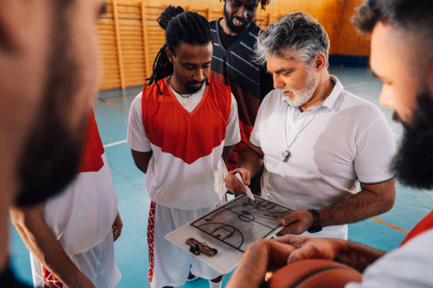 istock Interracial basketball team looking at clipboard, working on game plan. 2041100505