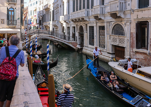Venice, Italy - September 5, 2022: One of the most recognizable tourist attractions in the world - a gondola cruise through the narrow canals in Venice