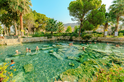 Pamukkale, Turkey - Aug 7,2023: Tourists happily immerse themselves in revitalizing thermal waters of Cleopatra Pools in Hierapolis, embracing soothing experience amidst the captivating ancient charm.