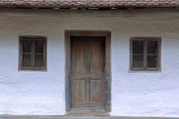 facade of old romanian traditional house with wooden door and two small windows