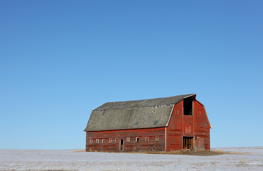 An old red barn on the prairie in winter.