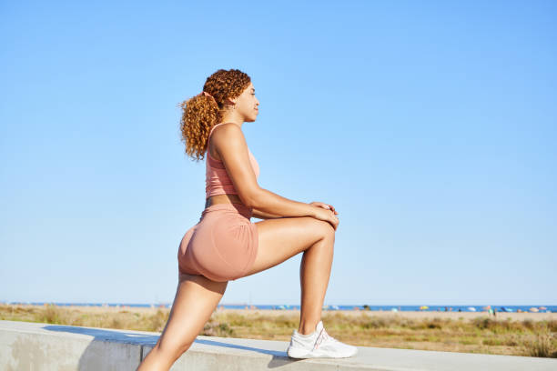 istock Sportswoman doing leg stretching exercises after running on the beach 2041208151