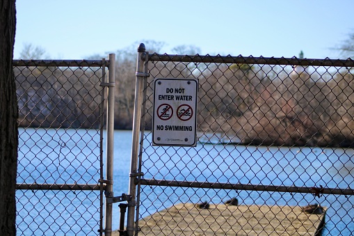 A sign posted on a metal gate that says no swimming.