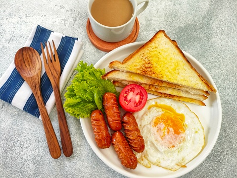 breakfast with toast, eggs, cocktail sausage, vegetables and accompanied by a cup of coffee