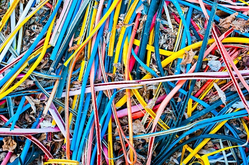 Striped wires for copper. Multi-coloured striped wire casings scattered on the ground like rainbow-coloured spaghetti.