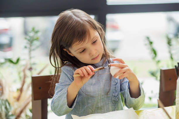 istock Child Concentrating on Painting Egg. 2041263637