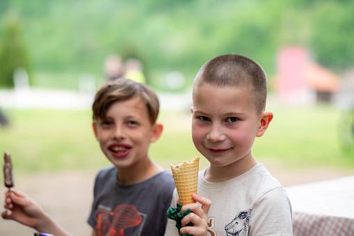 portrait of two happy boys outside eating ice cream and having fun