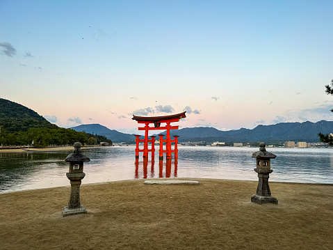 Miyajima, Itsukushima island, Japan - 13.11.2023. Miyajima, The famous Floating Torii gate with beautiful sunrise at the background, Itsukushima shrine, Hiroshima prefecture, Japan. Great floating torii. lanterns on a beach