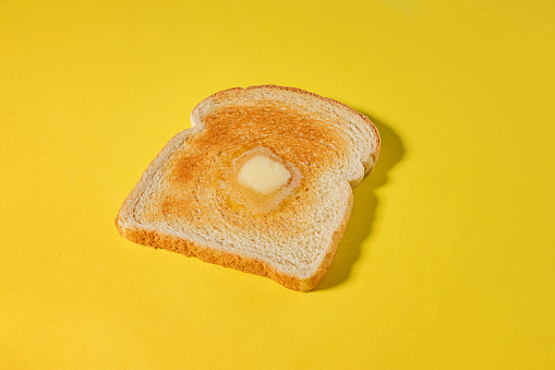 Bread slice, toast with a slice of butter melting, isolated on yellow background, breakfast food