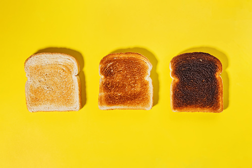 Different stages of toast, toasted square bread slices isolated on yellow background