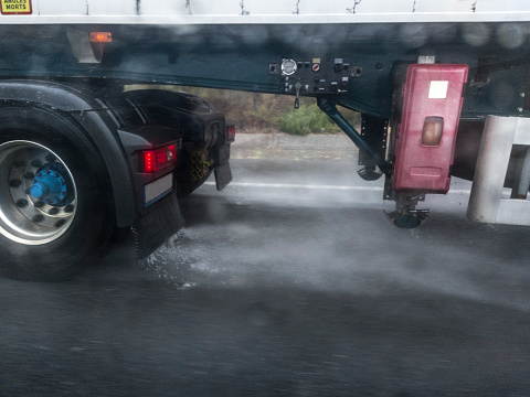 Truck wheels splashing water on road. Dangers driving near trucks