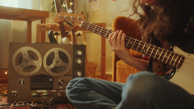 Musician Playing Guitar on Floor near Retro Reel-to-Reel Tape Recorder