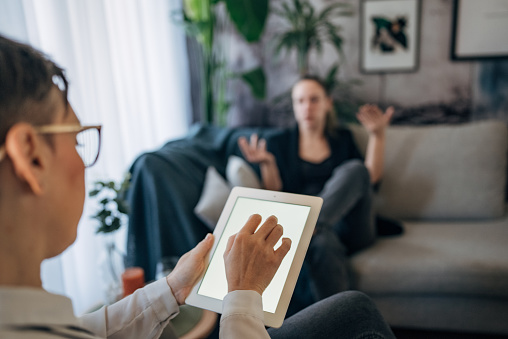 A professional is attentively showing content on a tablet to an individual during a session