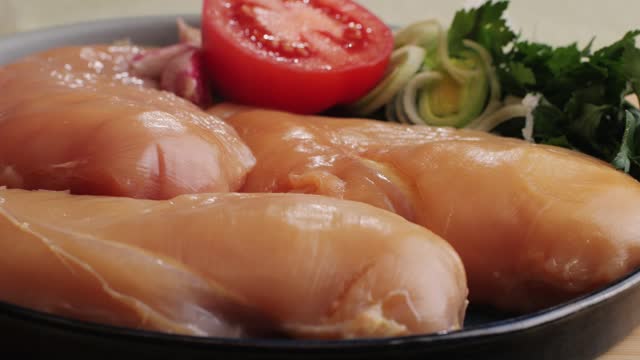 Raw chicken meat on plate close-up. Preparing raw food for cooking. Grilled chicken, duck, turkey kebab with vegetables.