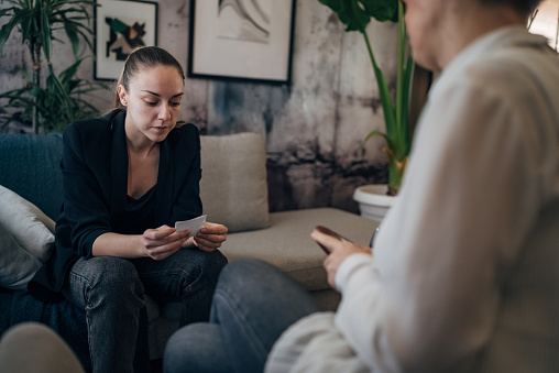 A professional therapist, in a serene and well-lit office, extends a medical prescription to a woman. The exchange signifies personalized care and attention, fostering trust and understanding between the professional and the patient.