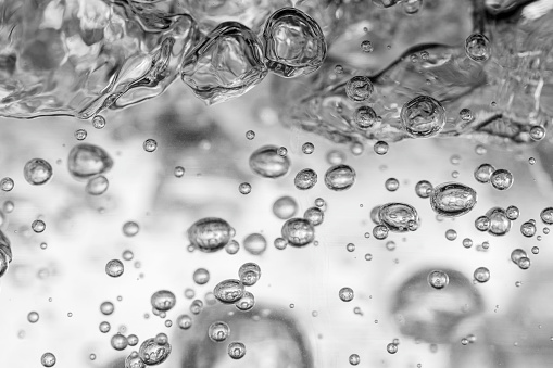 Close up of black and white transparent air bubbles in water.