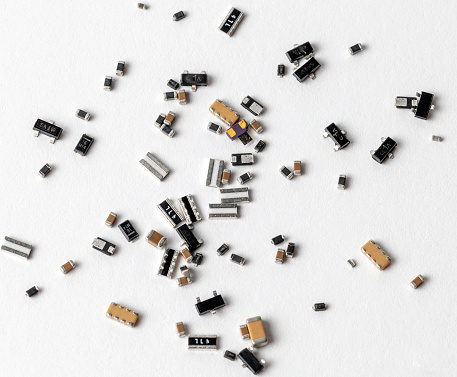 An array of various electronic components and microchips randomly scattered across a white surface.