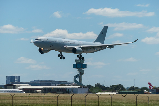 A Royal Australian Air Force Airbus KC-30A plane, the military version of an Airbus A330-200, registration A39-004, landing at Sydney Kingsford-Smith Airport as flight WNSR01.  The plane flew from the RAAF Airbase near Brisbane, stayed in Sydney for about 20 minutes, then departed for Cairns in far north Queensland. In the background is the air traffic control tower; a Virgin Australia B737-8FE, VH-VOL; and a Qantas Freight Airbus A330-202(P2F), VH-EBE. This image was taken from Mill Stream Lookout, Botany Bay on a hot and sunny afternoon on 25 February 2024.