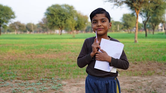 Kid, smile and portrait of student with books for education, study or learning isolated on a green field background.