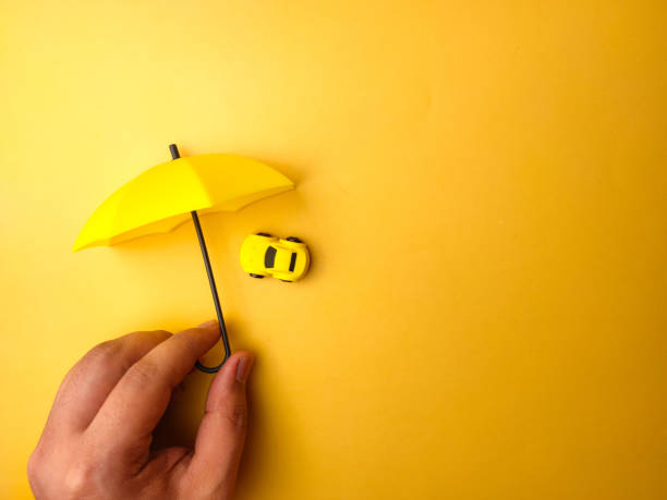 istock Someone hand holding yellow umbrella covered yellow car 2041560529