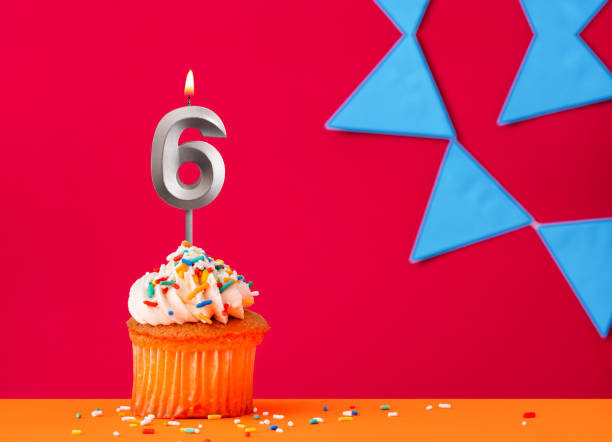 istock Number 6 candle with birthday cupcake on a red background with blue pennants 2041656132