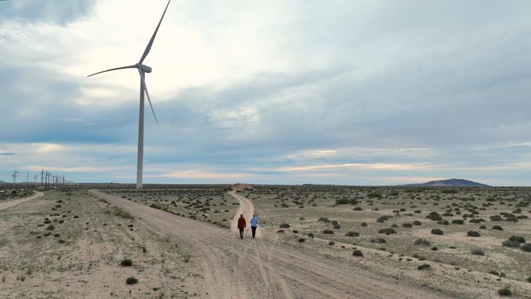 Aerial view of couple walking towards wind turbine