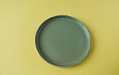 Empty green plate on yellow background. Top view. Copy space.