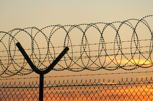 Part of the security fence around Sydney Kingsford-Smith Airport.    This image was taken from near Shep's Mound, Ross Smith Avenue, Mascot after sunset on 25 February 2024.