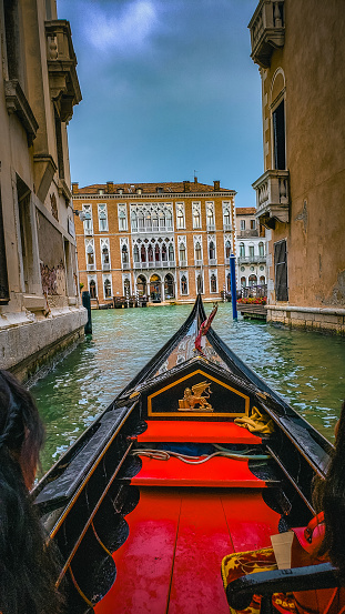 Venice, Italy - October 8, 2019: Asian tourists in a traditional gondola on the canals of Venice, Italy