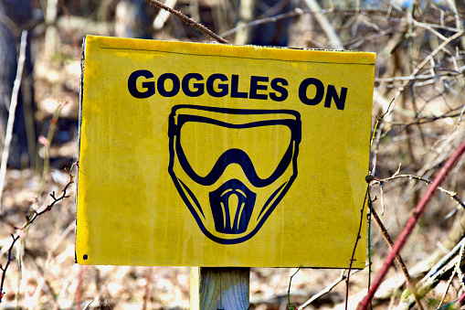 Loudoun County, Virginia, USA - February 25, 2024: A sign informs players to don their face mask and goggles at an outdoor paintball complex.