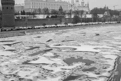 Climate change leads to global natural disasters, abnormal temperatures, heavy snowfalls, typhoons and droughts. Ice-covered winter Moscow River with a view of the Kremlin and the Kremlin embankment. Black and white.