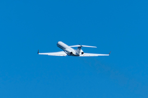 A Gulfstream G550 plane, registration N998NB, taking off from the third runway of Sydney Kingsford-Smith Airport and heading to Auckland. A trail of fumes is visible from her engines. This image was taken from Mill Stream Lookout, Botany Bay on a hot and sunny afternoon on 25 February 2024.