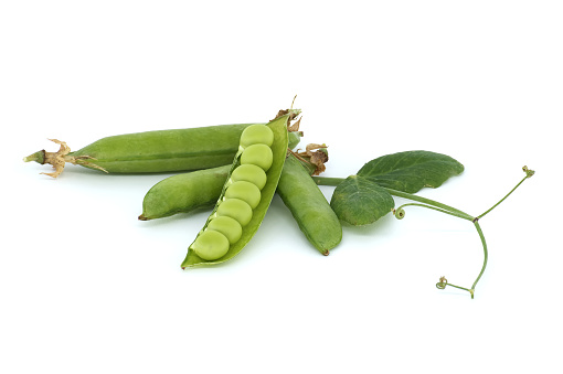 Green pea pods in wooden bowl isolated on white. Top view.