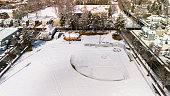Snowy sports playground is in the center of residential area. White neighborhood with houses and educational buildings in Madison, New Jersey