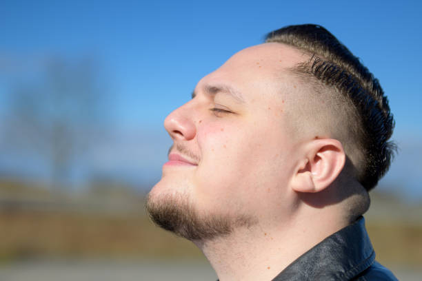 istock Young man enjoying the sun in a park with eyes closed 2041954277