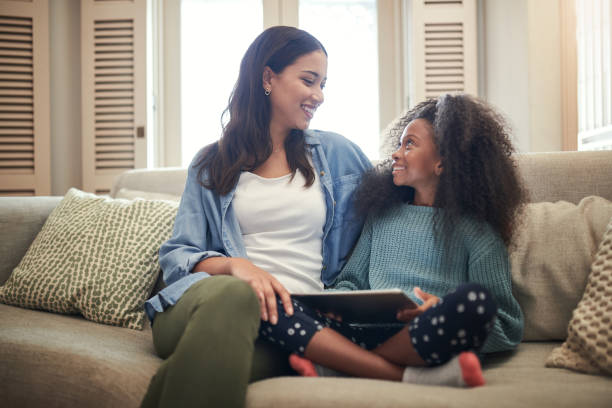 Shot of young girl using a digital tablet while sitting at home with her mother This app is teaching her everything she needs to know free girl download stock pictures, royalty-free photos & images