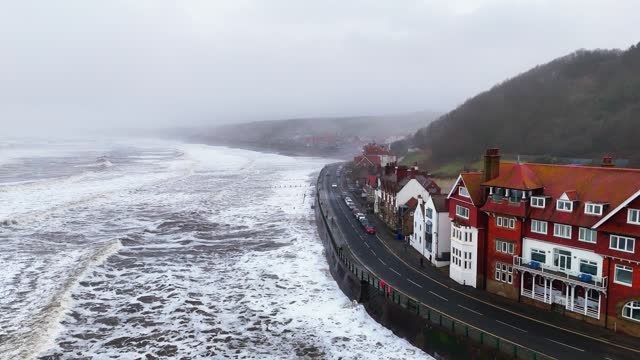 Stormy winter scene. Rough seas of the English coast with mist and fog. Aerial footage of the sleepy coastal town of Sandsend beach on the coast of north Yorkshire in England