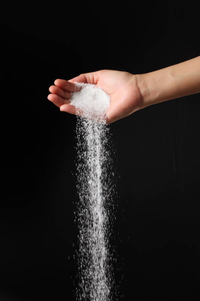 istock Hand sprinkling sugar on black background 2042030194
