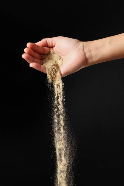 istock Hand sprinkling ground pepper on black background 2042030195