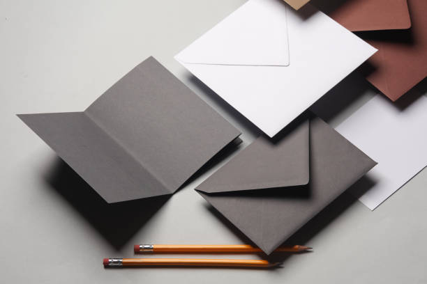 Floating envelopes and brochure, card, pens on gray background with shadow. Minimalism, modern business still life, creative layout